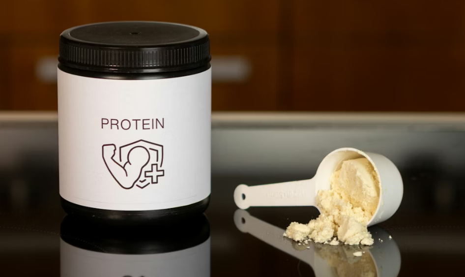 숟가락 옆에 있는 단백질 파우더 용기 사진