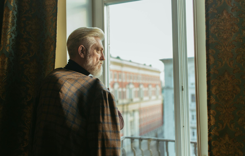 거실 창밖을 멍하니 바라보며 생각에 잠겨있는 노인 이미지