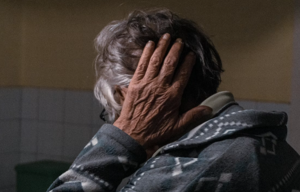 의자에 앉아 어지러운 듯 머리를 잡고 계시는 어르신 이미지