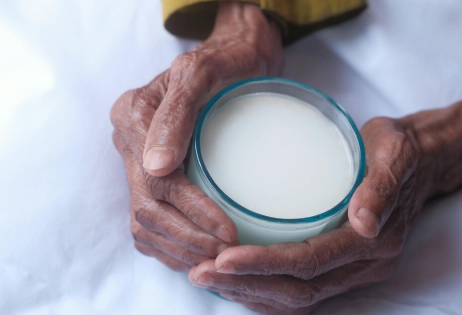 따뜻한 우유를 마시려는 노인의 손 이미지